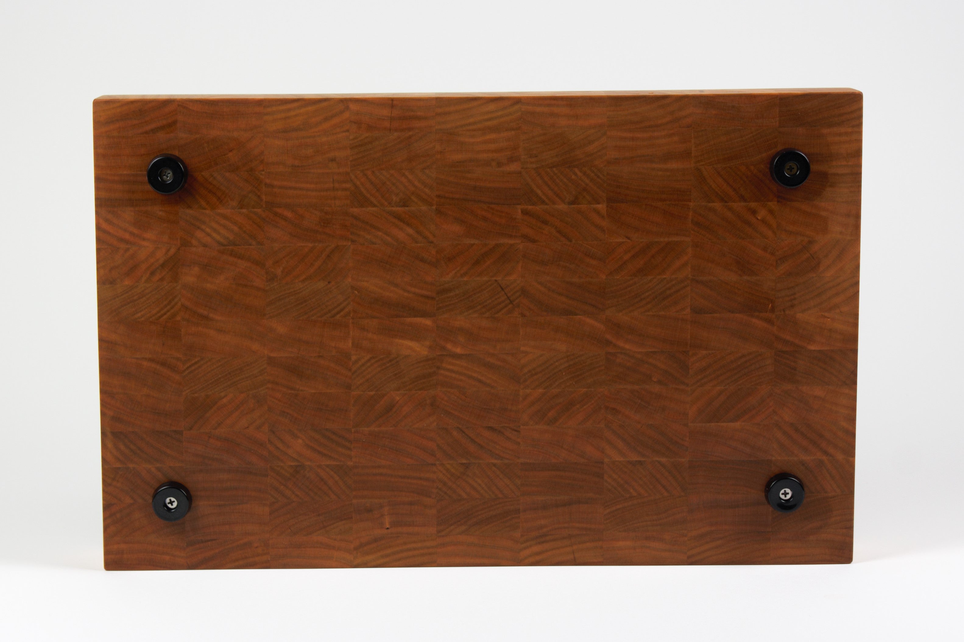 Cherry wood end grain cutting board with rich warm wood tones. Displaying a view of the bottom side with four cutting board feet.