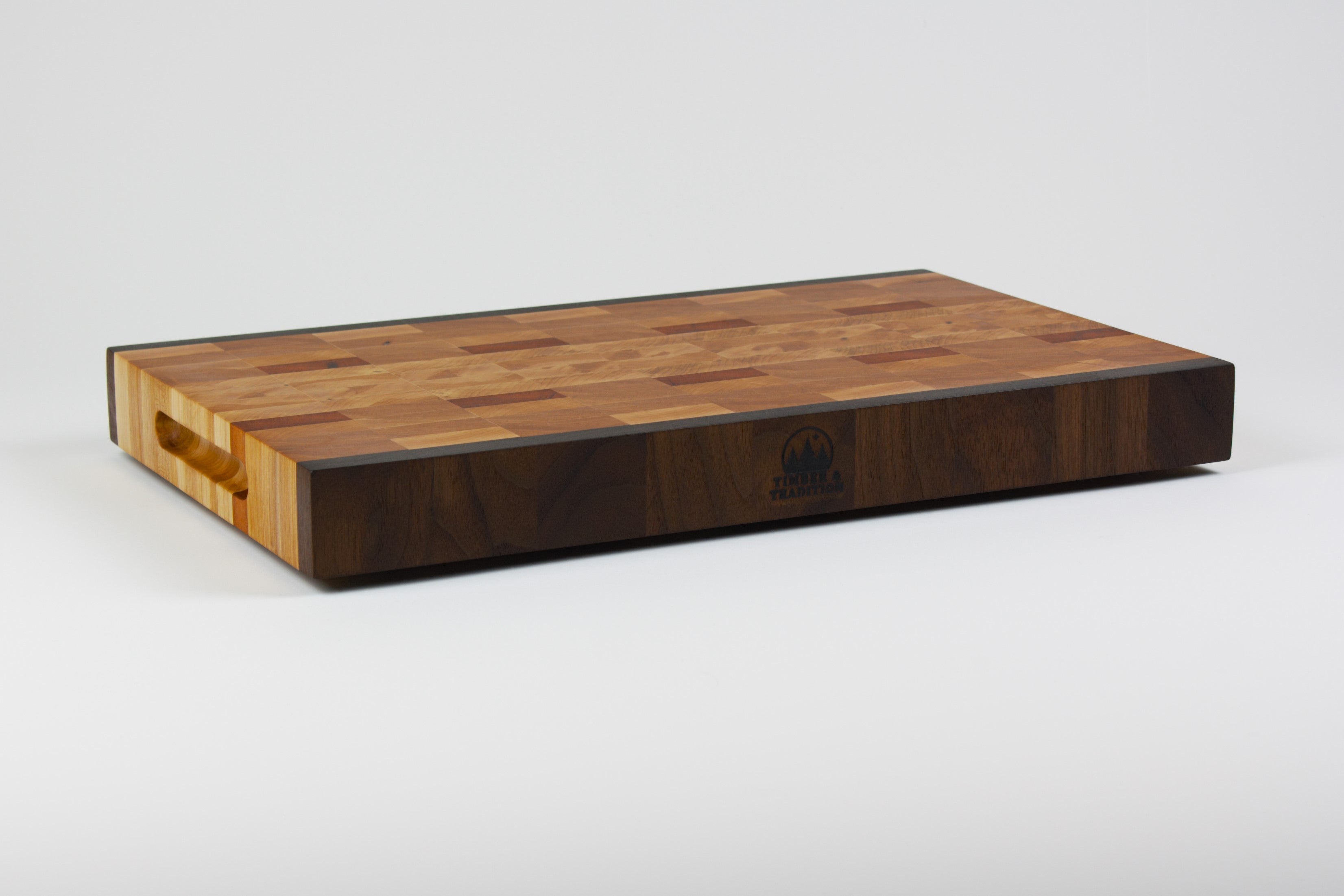 End grain cutting board made of rustic Hard Maple and accented with Tigerwood and Black Walnut. Front left corner view.