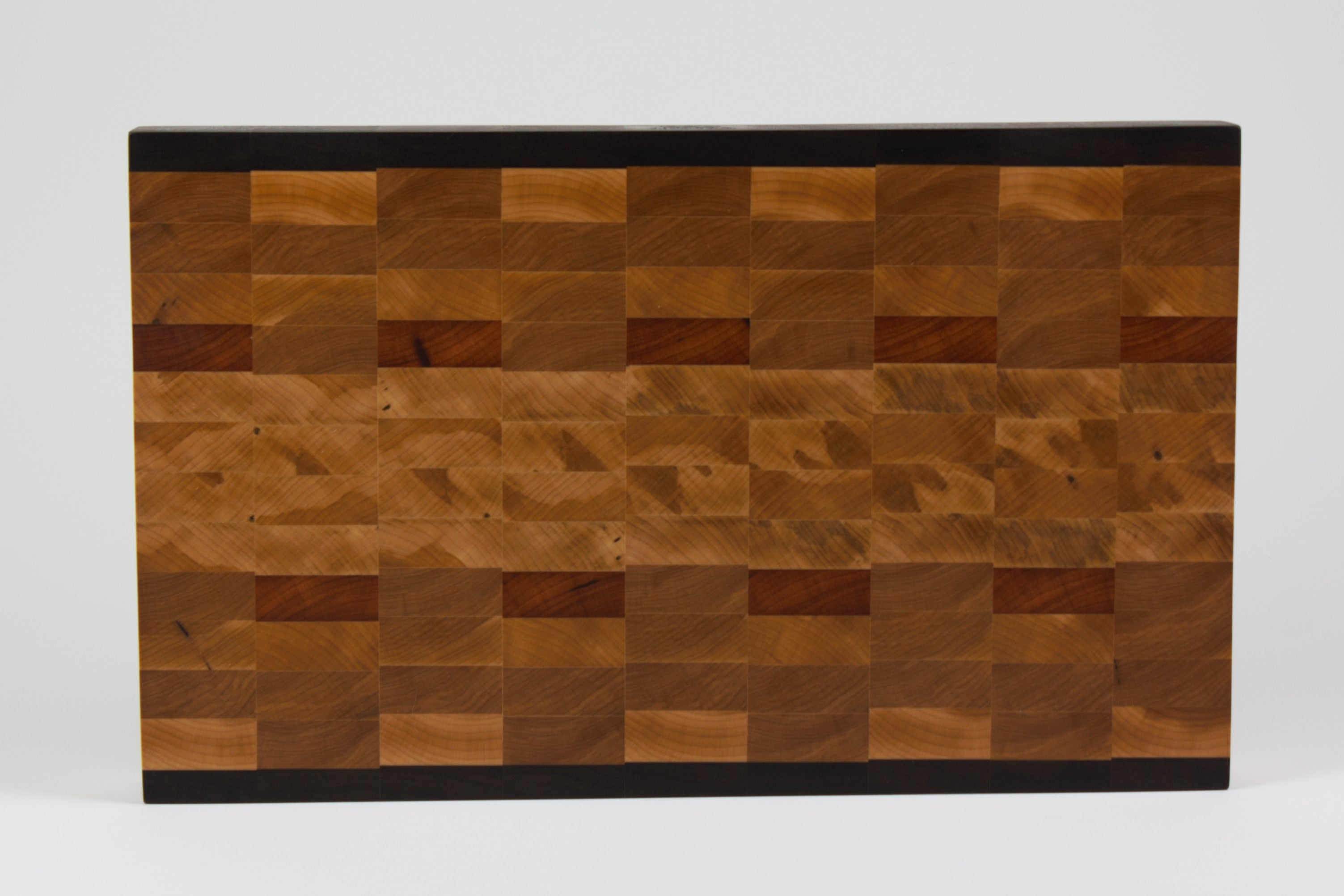 End grain cutting board made of rustic Hard Maple and accented with Tigerwood and Black Walnut. Straight on view of the cutting surface.