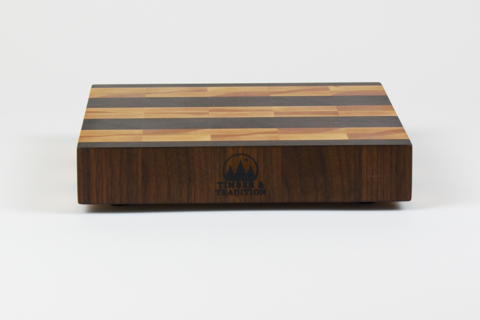 Luxurious Black Walnut and Maple cutting board, front view, displaying the Timber & Tradition logo.