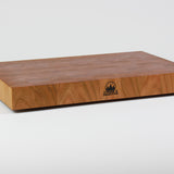 Cherry wood end grain cutting board with rich warm wood tones.  Timber & Tradition logo burned into center front. Front left corner view.