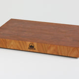 Cherry wood end grain cutting board with rich warm wood tones.  Timber & Tradition logo burned into center front. Front right corner view
