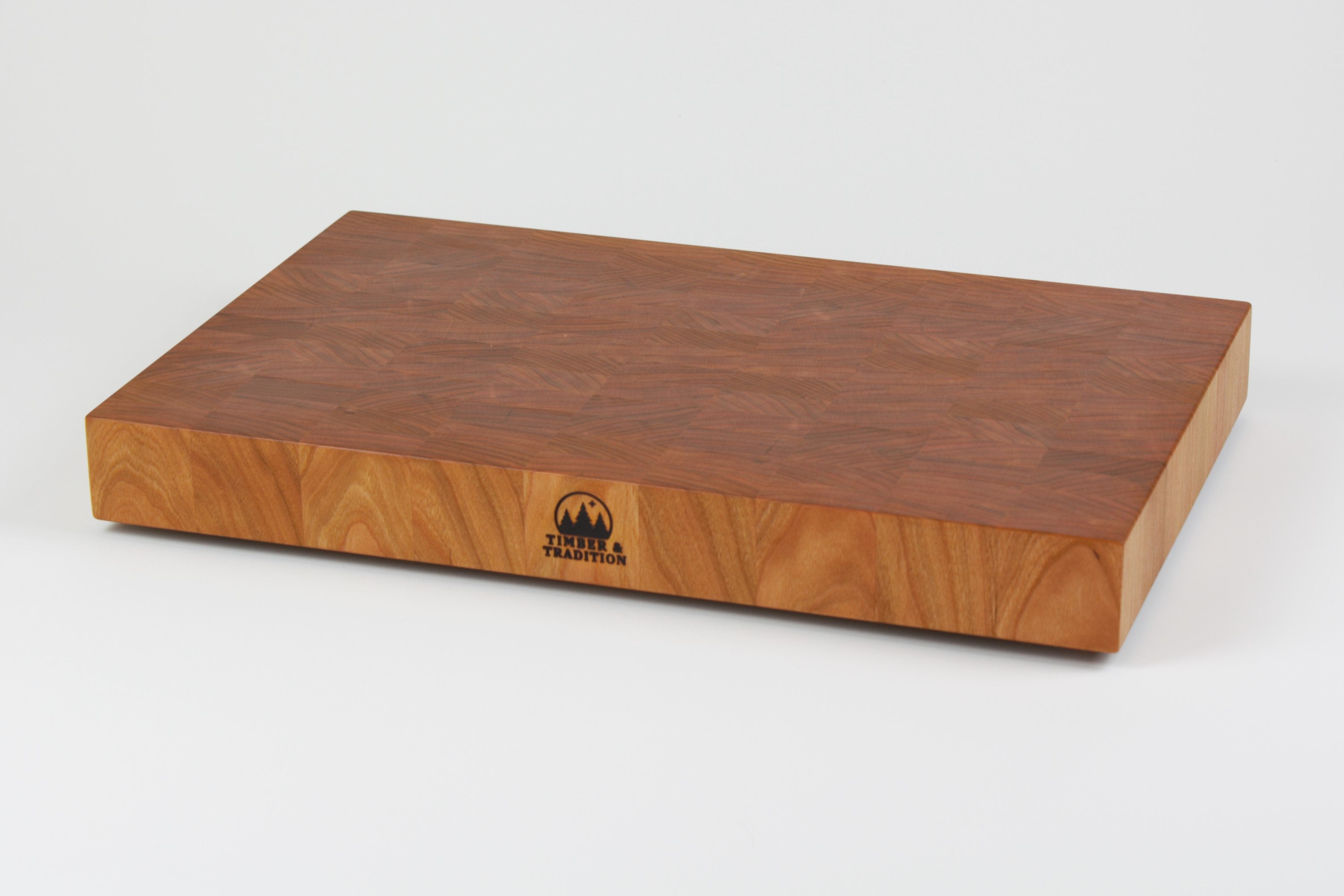 Cherry wood end grain cutting board with rich warm wood tones.  Timber & Tradition logo burned into center front. Front right corner view