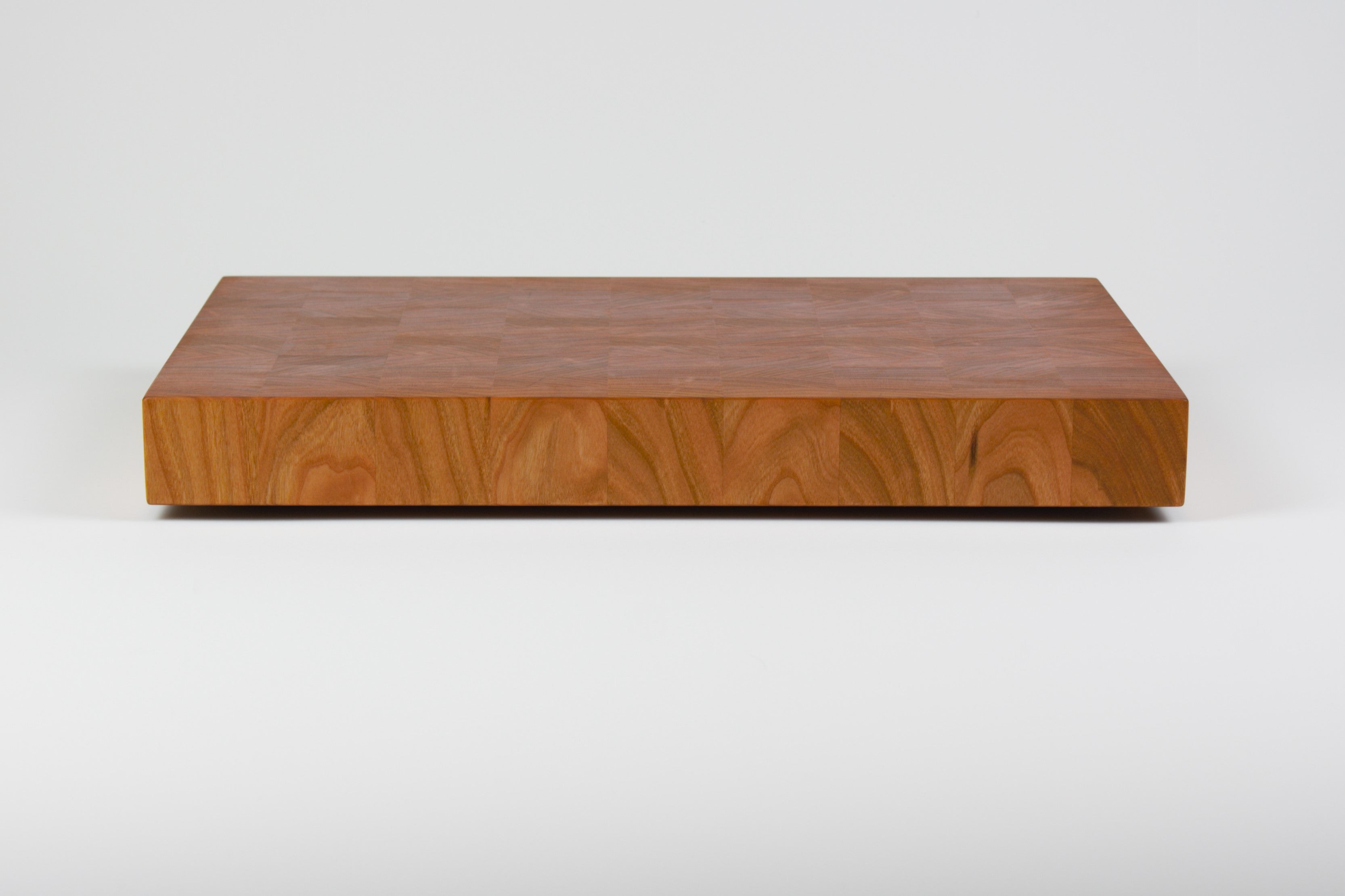 Cherry wood end grain cutting board with rich warm wood tones, rear view.