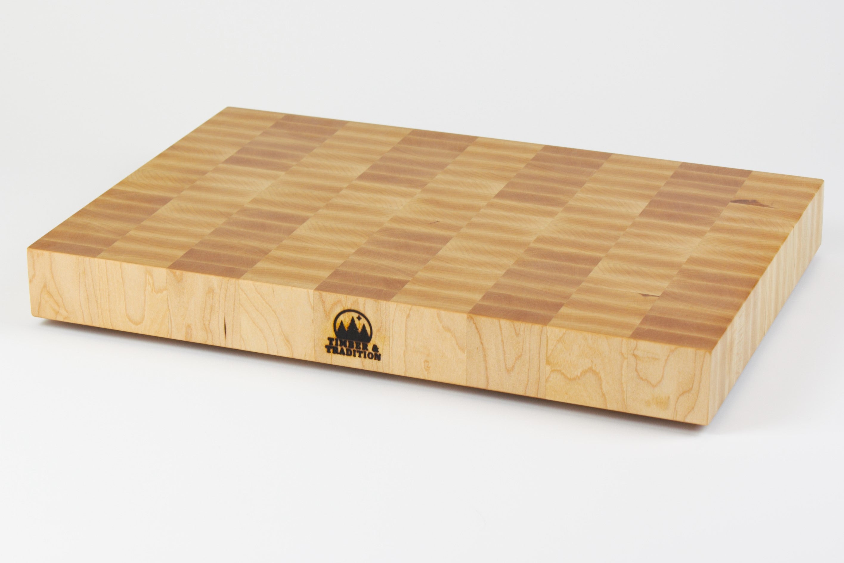 Classic Hard Maple cutting board with golden hues. The Timber & Tradition logo is burned into the center front, this is the front right corner view.