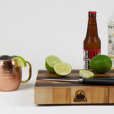 Maple and Black Walnut cutting board with cut limes, ginger beer, and Mezcal to prepare a Mezcal mule.