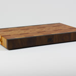End grain cutting board made of rustic Hard Maple and accented with Tigerwood and Black Walnut. Front left corner view.