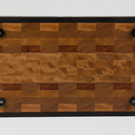 End grain cutting board made of rustic Hard Maple and accented with Tigerwood and Black Walnut. Straight on view of the bottom surface. Four cutting board feet mounted to board surface.